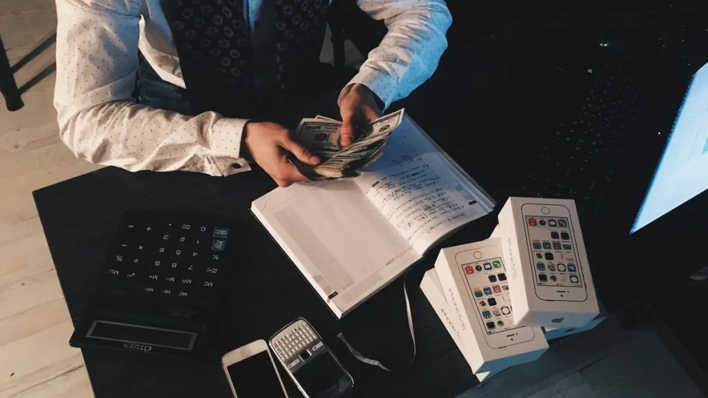 Persona con calculadora y dinero aprende cómo calcular la cuota de un préstamo